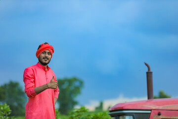 Obraz premium Technology and people concept, Portrait of young indian farmer with tractor