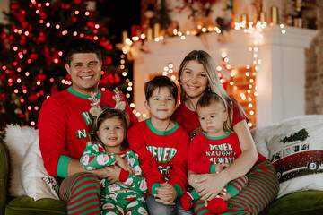 Obraz na płótnie Canvas Big family of five in Christmas pyjamas sitting together on a sofa.