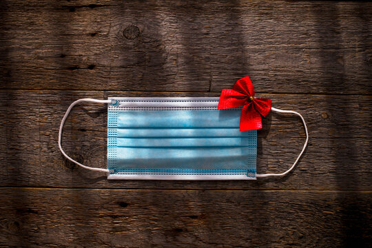 Medical mask as a gift with a red bow on a wooden background. - Powered by Adobe
