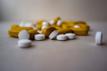 Fototapeta na wymiar Nutrition supplement pills, white and yellow medicine pills on grey and brown background, vitamin pills