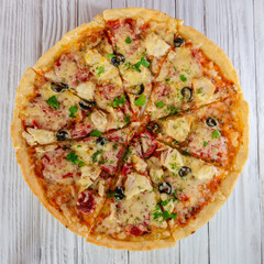 pizza with cheese vegetables and meat on a wooden background