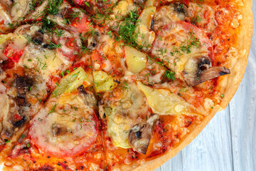 pizza with cheese vegetables and meat on a wooden background