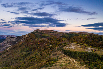 panoramic view of yellow autumn mountains against a background of blue haze and storm clouds filmed from a drone