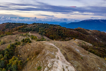 Fototapeta na wymiar panoramic view of yellow autumn mountains against a background of blue haze and storm clouds filmed from a drone