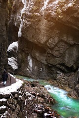 Tourists in snow-covered icicles at Partnachklamm, famous tourist destination. Partnachklamm in Garmisch-Partenkirchen, Bavaria