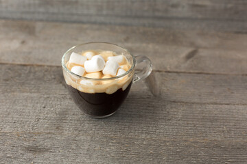 Cup of coffee with marshmallows on a wooden table. Street food.