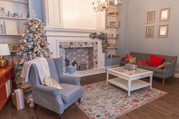Classic Christmas decorated interior room, New year tree with silver decorations. Modern blue classical style interior design apartment with fireplace and armchair. Christmas eve at home.