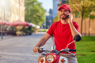 Young cheerful caucasian delivery man talking on phone