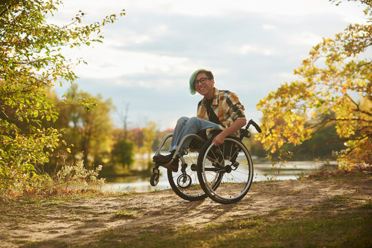 Disabled teen boy doing a wheelie in his wheelchair.