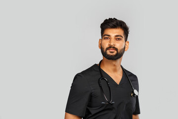 young indian male doctor or surgeon with stethoscope on gray background