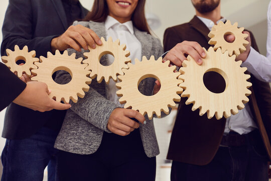 Company employees joining cogwheels as metaphor for effective business system and management