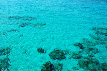 Top view of the sandy bottom and rocks through clear clear sea water, turquoise color