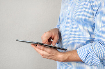 A man in a shirt holds a tablet. Businessman