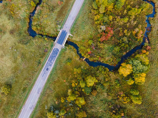 Aerial view of the road with a picturesque autumn landscape. Bright fall colors, Drone shooting of scenic autumn backgrounds. Top view