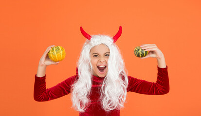 shouting devil child with white hair hold pumpkin vegetable wear horns costume of imp on halloween...