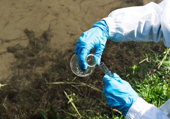 gloved hand collects water in a test tube.