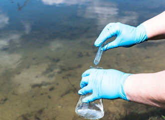 Hand in a blue glove holds a test tube.