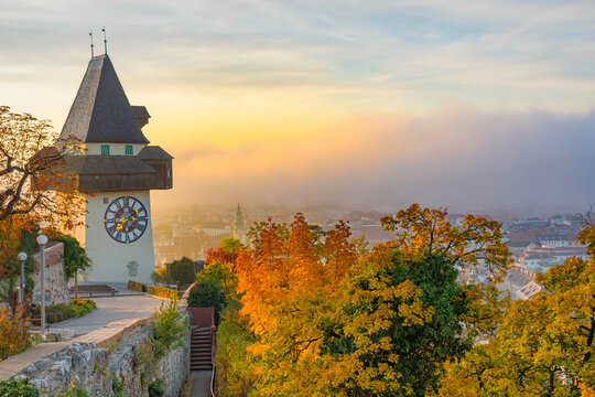 The famous clock tower on Schlossberg hill, in Graz, Styria region, Austria, at sunrise. Beautiful foggy morning over the city of Graz, in autumn