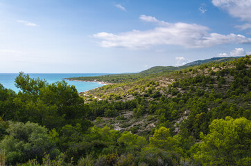 Fototapeta na wymiar Natural landscape of Sierra de Irta Park beside the sea with its beautiful beaches on a summer day with blue sky and clouds, Peniscola, Castellon, Spain