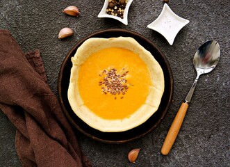 Pumpkin puree soup in an edible bread plate on a brown tray on a gray concrete background. Pumpkin recipes.