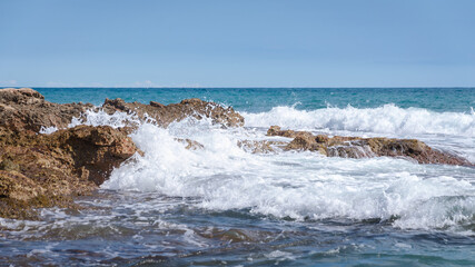 Fototapeta na wymiar Sea waves break against the rocky coastline in Sierra de Irta Natural Park, Castellon, Spain