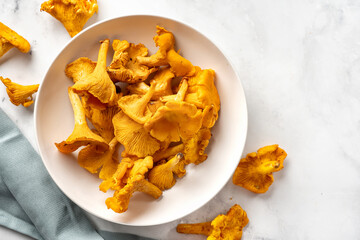 Top view of white plate with fresh chanterelles mushrooms