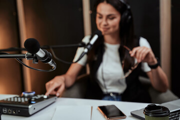 Close up of microphone in studio. Young female radio host moderating a live show in the background