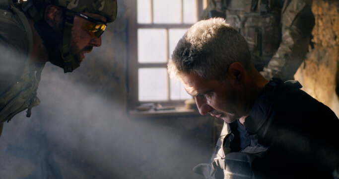 Angry soldier interrogating mature terrorist