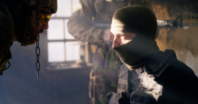 Angry soldier interrogating mature terrorist