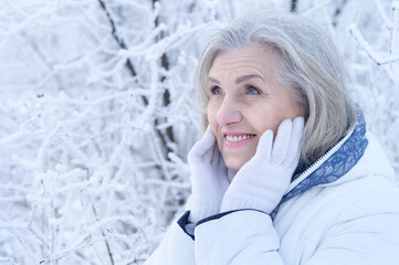 Happy beautiful senior woman posing in snowy winter park