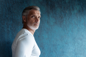 Casual Grey-haired Mature handsome man portrait over dark blue wall background