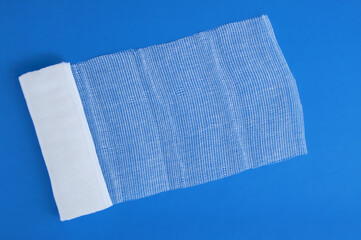 Medical cotton bandage on blue background. View from above.