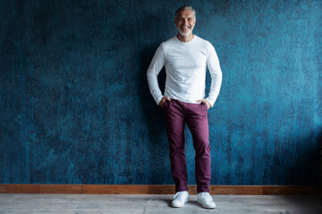 Casual Grey-haired Mature handsome man portrait over dark blue wall background
