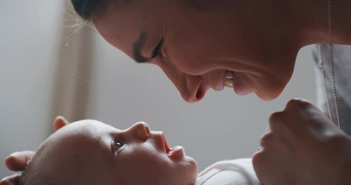 Authentic close up shot of young neo mother is playing with her newborn baby in a nursery in a morning.