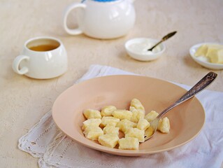 Lazy dumplings or gnocchi from cottage cheese in a clay plate on a light concrete background. Served with sour cream, butter. Dishes from cottage cheese. Healthy breakfast.