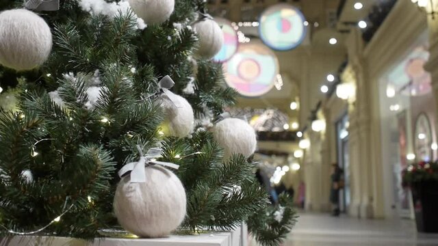 A girl touches a ball of thread hanging on a Christmas tree in a shopping center
