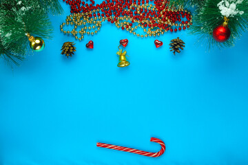 Christmas background of blue pine branch in a row of cones beads and sweets.