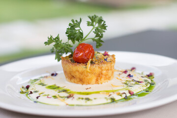 Close up on a gourmet flan with fondue cheese, resting on a restaurant table top.