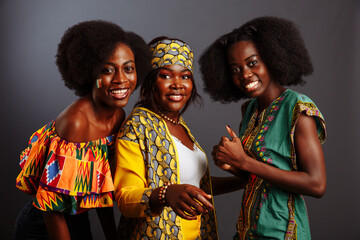 Three young beautiful African fashion models have fun and laughing in traditional dress. Women from...