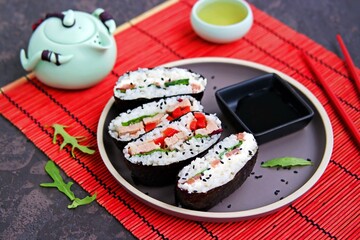 Sushi sandwiches with baked duck, spinach and sweet pepper on a brown clay plate on a dark concrete background.