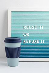 Reusable coffee cup and letterboard with text reuse it or refuse it. Zero waste sustainable lifestyle
