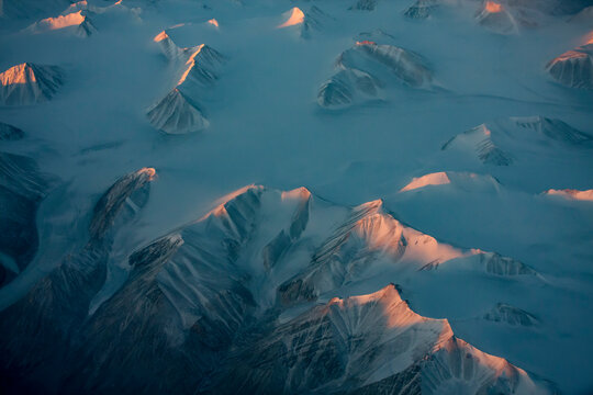Aerial view of snowy mountain peaks of Greenland during sunset