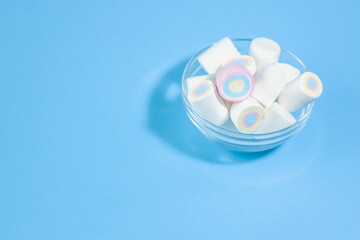 Mini marshmallow sweets on light blue background with free space for heading