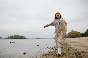 A young girl walks along the beach. Blonde girl walks in the Park near the lake