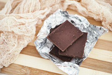 Pieces of dark broken chocolate in wrapping foil.