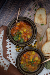 Celery, carrot and potato soup in ebameled bowls on dark table, copy space