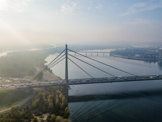 Aerial drone view. North bridge in Kiev in the rays of a sunny morning. Autumn haze in the air, cars are driving across the bridge.