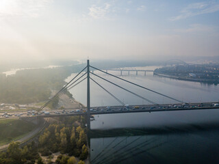 Aerial drone view. North bridge in Kiev in the rays of a sunny morning. Autumn haze in the air, cars are driving across the bridge.