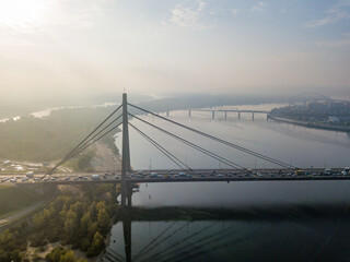 Aerial drone view. North bridge in Kiev in the rays of a sunny morning. Autumn haze in the air, cars are driving across the bridge.