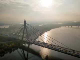 Aerial drone view. North bridge in Kiev in the rays of a sunny morning. Autumn haze in the air, cars are driving across the bridge.